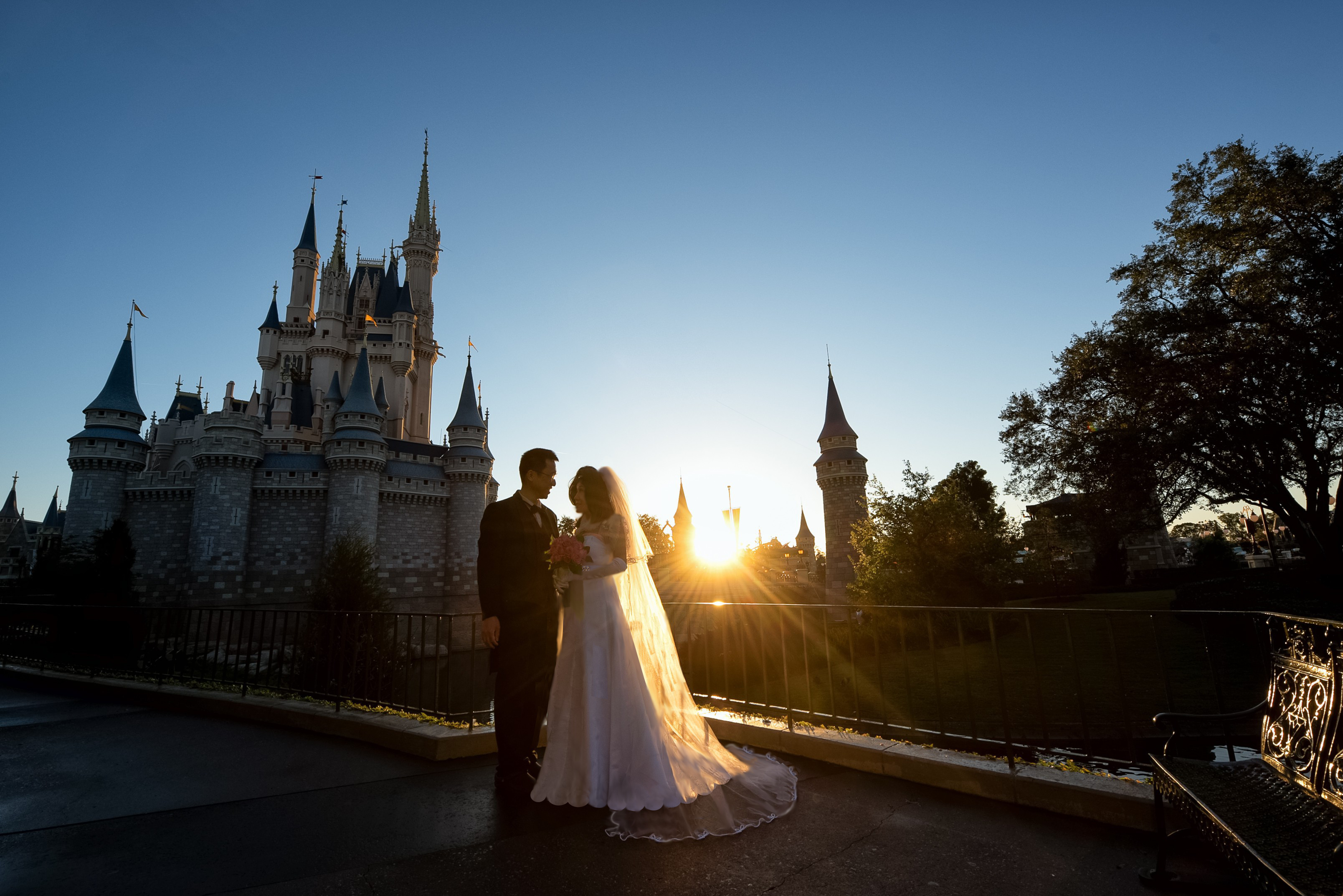 A wedding portrait taken in front of a Disney castle